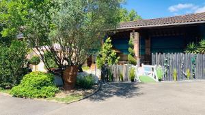 a house with a fence and a tree in the driveway at Studio Au Clos Saint Georges , piscine et Spa in Saint-Jory