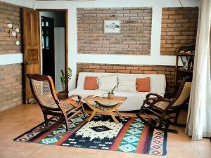 a living room with a couch and two chairs at Hideout Surf House in Transito