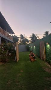 Un par de perros sentados en el césped de un patio. en Souzas House, en Vera Cruz de Itaparica