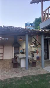 un patio con una mesa y bancos bajo un techo en Souzas House, en Vera Cruz de Itaparica