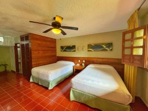 a bedroom with two beds and a ceiling fan at Hotel Casa Colonial Cozumel-Dog Friendly in Cozumel