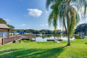 a house with a dock and a palm tree next to a lake at Lakeland Cottage with Pool Access and Screened Porch! in Lakeland
