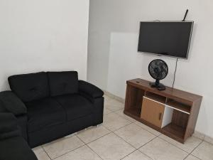 贝洛奥里藏特Casa espaçosa em Belo Horizonte的客厅配有黑色沙发和平面电视。