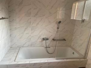 a white bath tub with a shower in a bathroom at Sunrise Cottage Golfview Lodge in De Deur +6 photos