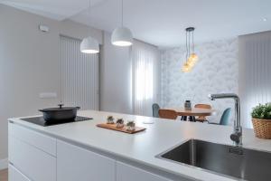a white kitchen with a sink and a table at Casa A LAXE in Vilagarcia de Arousa