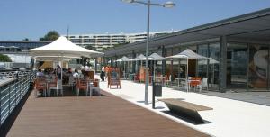 a boardwalk with tables and chairs and white umbrellas at Beach Cosy Boat in Oeiras