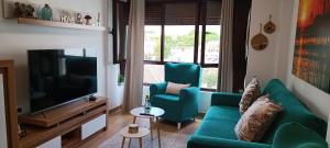 a living room with a green couch and a television at "EL JUNCAL" APARTAMENTO TURISTICO Parking gratuito in Cabra