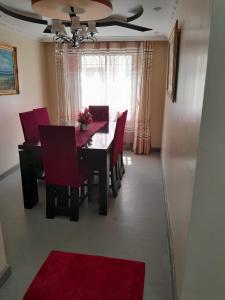 a dining room with a table and red chairs at Mypropertymychoise Nyayo estate in Nambale