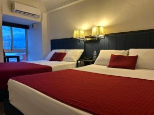 Una habitación de hotel con dos camas con almohadas rojas. en Choco's Hotel, en Villahermosa