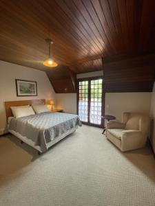 カンポス・ド・ジョルドンにあるVilla Panoramaの広いベッドルーム(ベッド1台、椅子付)