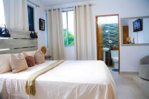 a bedroom with a large white bed and a bathroom at Casa tropical con piscina privada in Punta Cana +20 photos