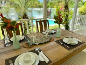 a wooden table with plates and wine glasses on it at Villa 4Bdrms 3.5baths with pool, Jacuzzi and Starlink WiFi in Las Terrenas +18 photos