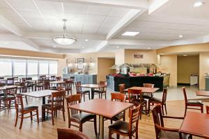 a dining room with tables and chairs and a kitchen at Best Western Plus Kansas City Sports Complex Hotel in Kansas City