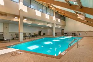 a large pool in a building with chairs and tables at Best Western Plus Kansas City Sports Complex Hotel in Kansas City