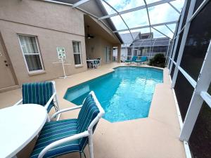 a swimming pool with two chairs and a table at Awesome golf views from your pool Villa Southern Dunes in Haines City