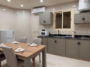 a kitchen with a wooden table with chairs and a tableasteryasteryasteryasteryastery at لامار بارك للأجنحة الفندقية in Tabuk