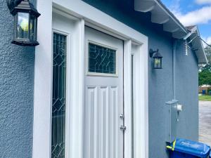 eine weiße Tür in einem blauen Haus mit zwei Fenstern in der Unterkunft Getaway Clubhouse in Winter Haven