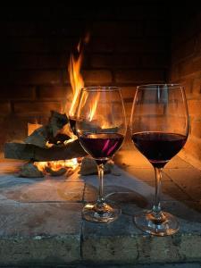 two glasses of wine sitting in front of a fireplace at Chalé Portal Lazer Propriedade Inteira in Gonçalves