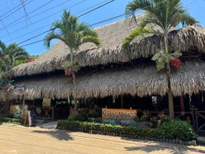 a restaurant with palm trees and a straw roof at Prima Luna Palomino in Palomino