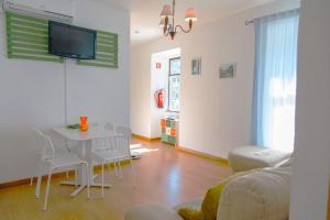 Una sala de estar con una mesa y un televisor en la pared. en Arcadas da Vila, en Manteigas