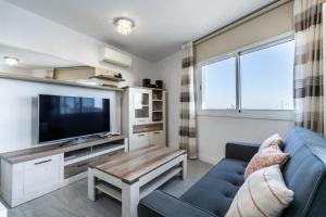 a living room with a blue couch and a tv at El rinconcito with sea view in Los Menores