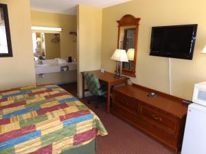 a hotel room with a bed and a desk and a television at Regency Inn in Concordia