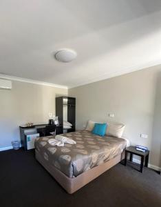 een slaapkamer met een groot bed en een bureau bij Copper City Motel in Cobar