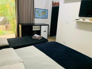 伯迪亚哥SUÍTE PRIVATIVA RIVIERA & ITAGUARÉ 100mts de 2 praias!的一间卧室，配有一张床和一张带电视的书桌