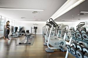 a woman walking through a gym with tread machines at InterContinental Genève by IHG in Geneva