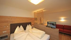 een slaapkamer met een bed met witte kussens en een televisie bij Chalet Findeisen in Ramsau am Dachstein