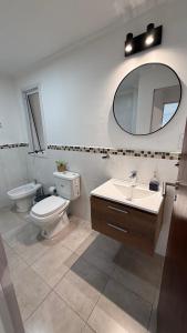 une salle de bain avec toilettes, lavabo et miroir dans l'établissement Departamento Ama con estacionamiento para vehículos chicos, à Villa Dolores