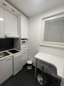 a kitchen with white cabinets and a table and a window at Dreamscape City Center in Belgrade