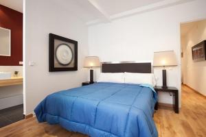 バルセロナにあるAB Eixample Viladomat Apartmentsのベッドルーム1室(大型ブルーベッド1台、ランプ2つ付)