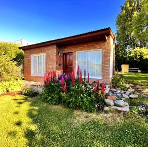 a small brick house with flowers in front of it at La Veranada in El Calafate