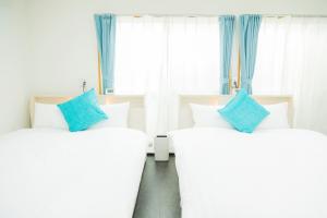two white beds with blue pillows in a room at 貸切戸建て Private House Sleep Man in Kagoshima