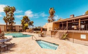 a pool in front of a building with palm trees at Rustic Farmhouse Old Town Condo W Patio & Pool in Scottsdale