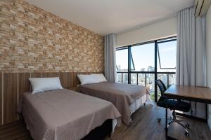 a hotel room with two beds and a desk and a window at Metropolitan Flats in Curitiba +54 photos