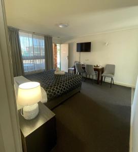 a hotel room with a bed and a table and chairs at Fig Tree Motel in Narrandera