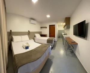 a hotel room with two beds and a television at Mar de Maragogi Flats in Maragogi