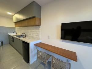 a kitchen with a sink and a tv on the wall at Mar de Maragogi Flats in Maragogi