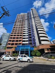 two cars parked in front of a tall building at Flat Beira Mar Meireles in Fortaleza