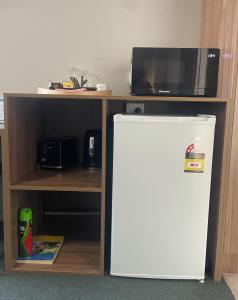 a white refrigerator under a microwave and a shelf at Fig Tree Motel in Narrandera