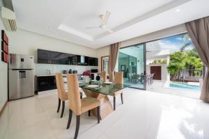 een open keuken en eetkamer met een glazen tafel en stoelen bij Relax & Enjoy Stay! Elegant 3BR Pool Villa Talosy in Rawai Beach