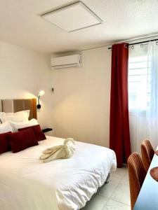 a bedroom with a white bed with a red curtain at T1, Le Bec Rose, neuf, 8 min aéroport in Sainte-Clotilde