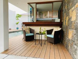 a patio with chairs and a table next to a pool at Belle Haven GF 1bedroom flat in Mont Choisy