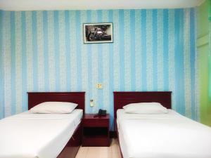 two beds sitting next to each other in a room at Woodlands Inn in Bangkok