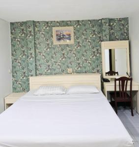 a bedroom with a bed and a desk with a mirror at Woodlands Inn in Bangkok +2 photos