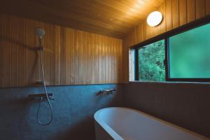 ein Badezimmer mit Badewanne und Fenster in der Unterkunft ëighten Private Guesthouse Yoga Retreat 一棟貸切古民家宿エイテン in Hokuto