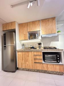 une cuisine avec des armoires en bois et un réfrigérateur en acier inoxydable dans l'établissement #2 Apto Top próx Metrô-Allianz Parque-Pró Magno, à São Paulo