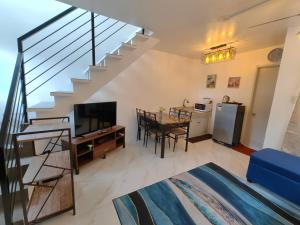 a living room with a dining room table and a staircase at Phirst Batulao Staycation in Tagaytay